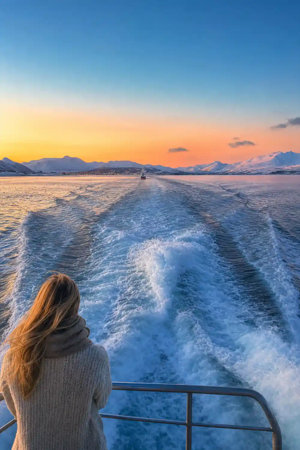 Boat wake at sunset with snow-covered mountains