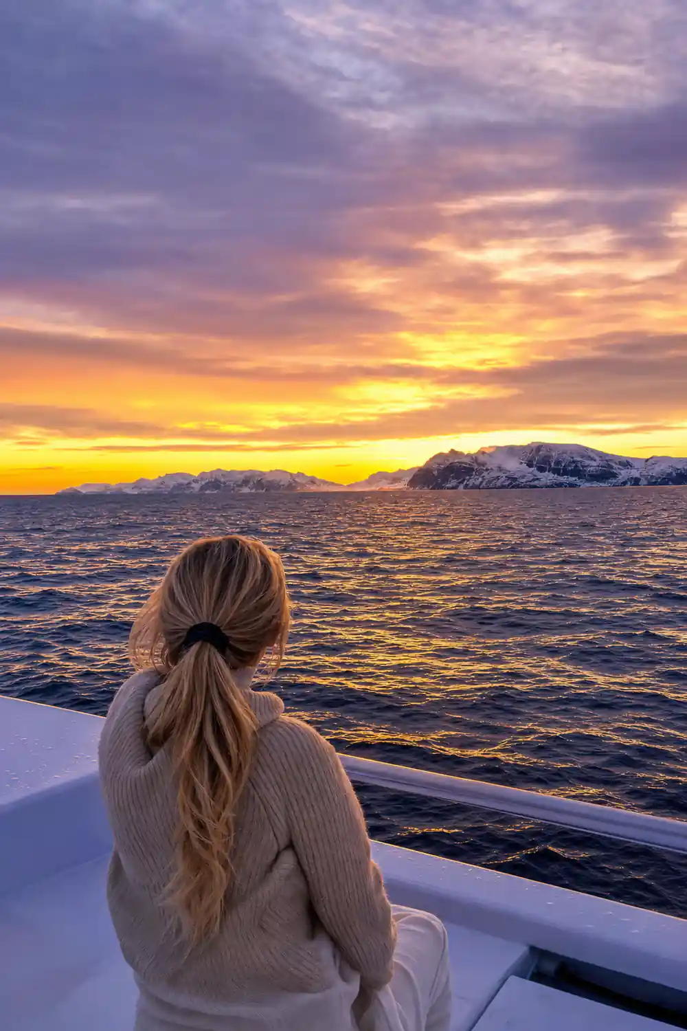 Dramatic sunset sky over snow-covered mountains from boat