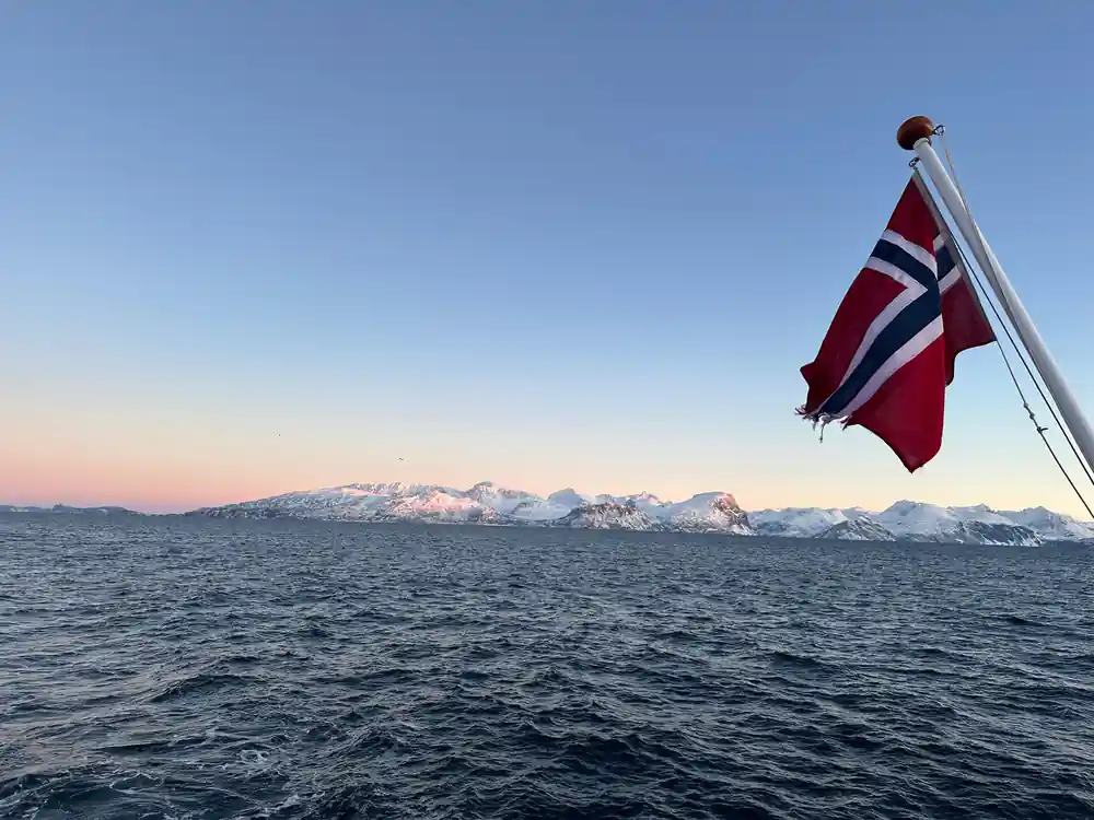 Norwegian flag on boat with snow mountains background
