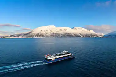 Research vessel sailing past snow-covered mountain across blue water