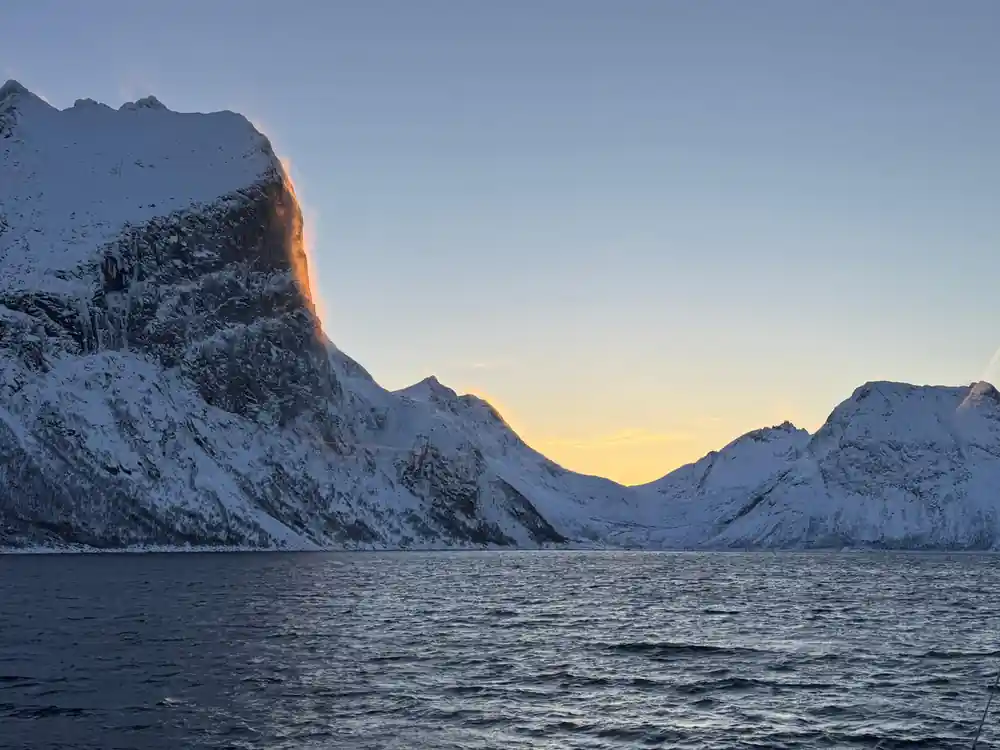 Snow-covered mountain peak at sunset reflected in water