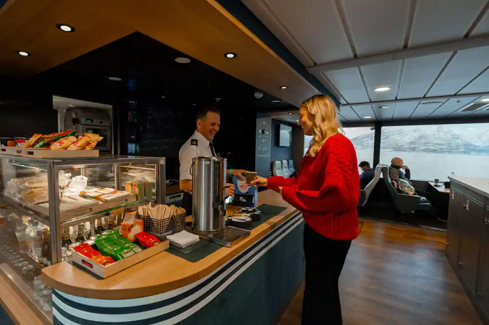 Woman in red jacket at boat cafe counter with pastries